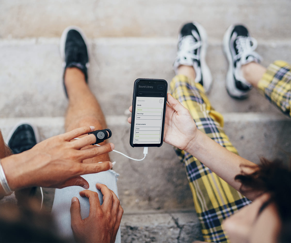 Friends co-making beats with a music gadget